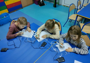 Troje uczniów wykonują dekoracje świąteczne na świetlicy długopisami 3D