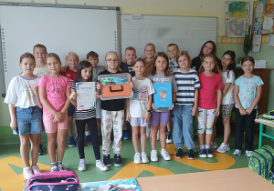 Uczniowie z nauczycielem trzymają certyfikat programu Aktywni Błękitni