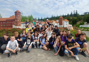 Zdjęcie grupowe klas piątych na tle mapy Kompleksu Jura Park