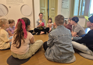 Uczniowie siedzą i oglądają stare zabawki w Muzeum Włókiennictwa w Łodzi