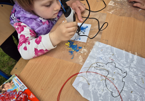 Dziewczynka wykonuje pracę długopisie 3D podczas festynu szkolnego