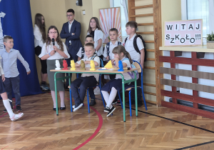 Uczniowie siedzą za stolikiem i mówią swoje role