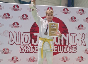 Zdjęcie chłopca stojącego na podium z medalem w ręku