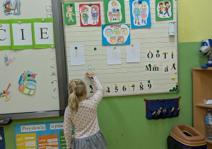 Uczennica układa litery przy tablicy