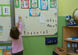 Uczennica przypina litery przy tablicy