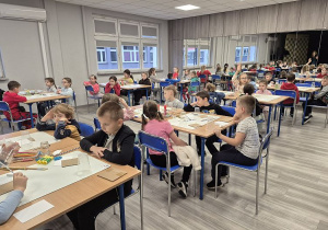 Uczniowie pracują przy stolikach w ośrodku kultury