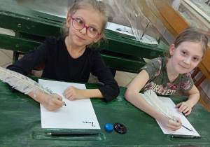 Dwie dziewczynki wykonują rysunki w Muzeum Oświaty w Łodzi podczas zajęć edukacyjnych