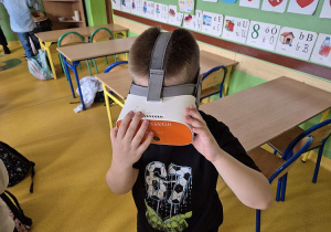 Uczeń w okularach 3D podczas zajęć teatralnych ogląda bajki