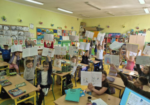 Dzieci z klasy 2 pokazują swoje prace w zeszytach